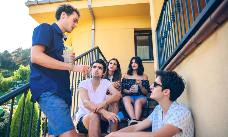 Young people talking outdoors sitting on home stairs steps