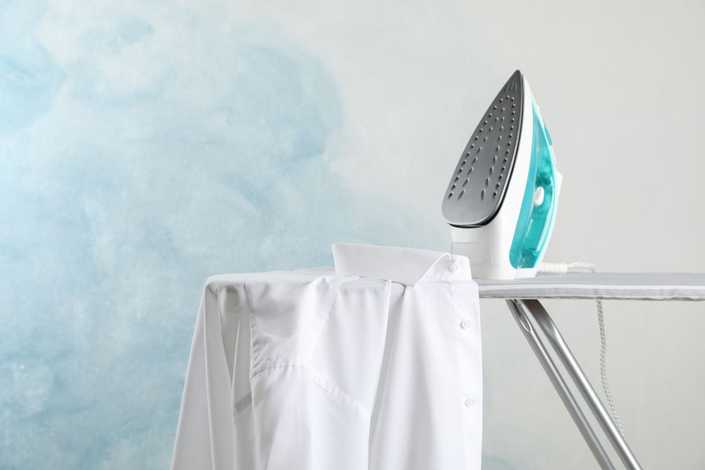 Iron and shirt on ironing board, space for text