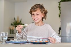 Cheerful boy eating rolls at home