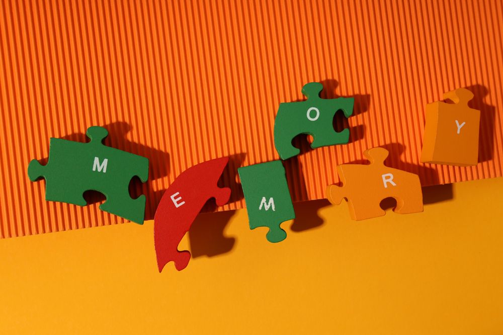 Orange paper duotone background with puzzle pieces spelling out the word “Memory”