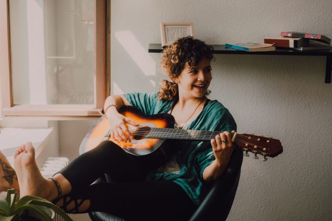 Content woman playing guitar at home