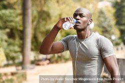 Healthy male drinking from a water bottle in an outdoor park 0PV6a4