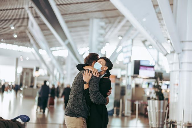 Traveler man hugging woman at airport arrival gate