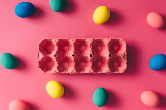 Colorful Easter eggs on pink background with carton