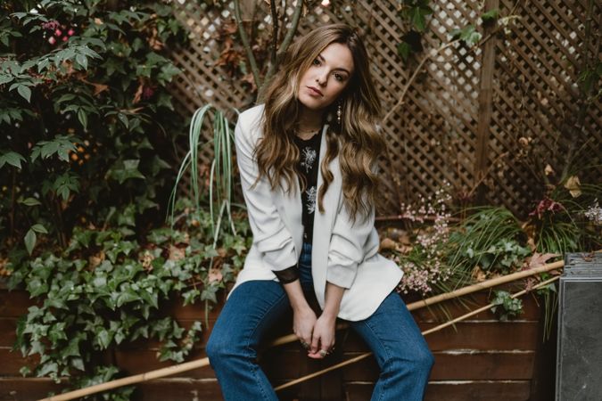 Woman sitting on planter in garden