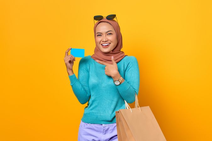 Muslim woman giving thumbs up with shopping bags and credit card