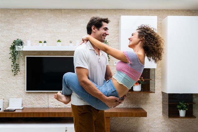 Smiling couple embracing in modern living room near TV