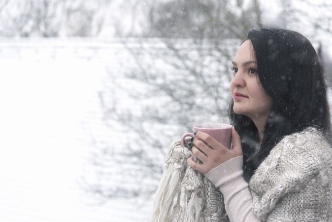 Woman drinking hot beverage under snowfall