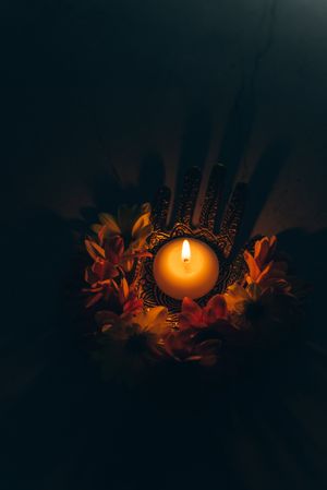 Top view of lit candle surrounded by flowers in dark room