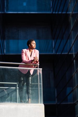 Proud woman in smart business attire leaning outside building looking in the distance