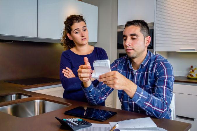 Couple in conflict reviewing their bills together in the kitchen