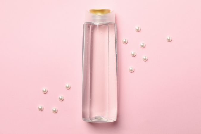 Blank shampoo bottle on pink background, space for text