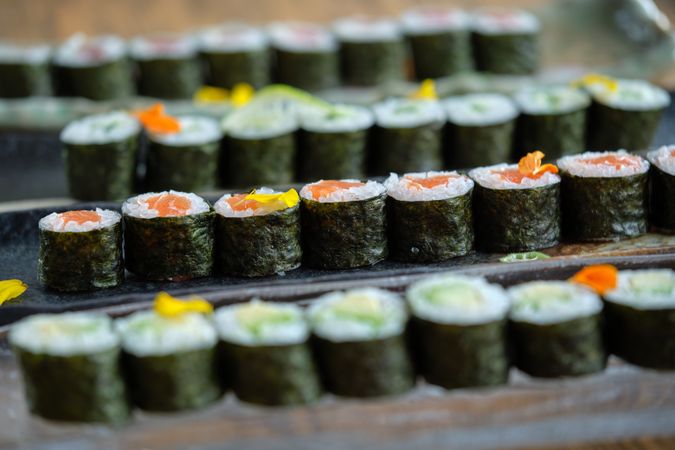 Sushi rolls with salmon on trays placed on wooden table