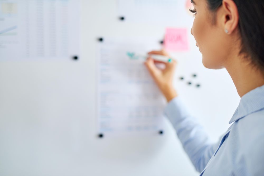 Back view of brunette woman writing on board for work
