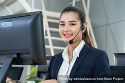 Smiling female speaking on headphones in call center 4mlze5