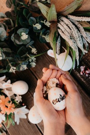 young woman holding an easter egg painted by children with flowers