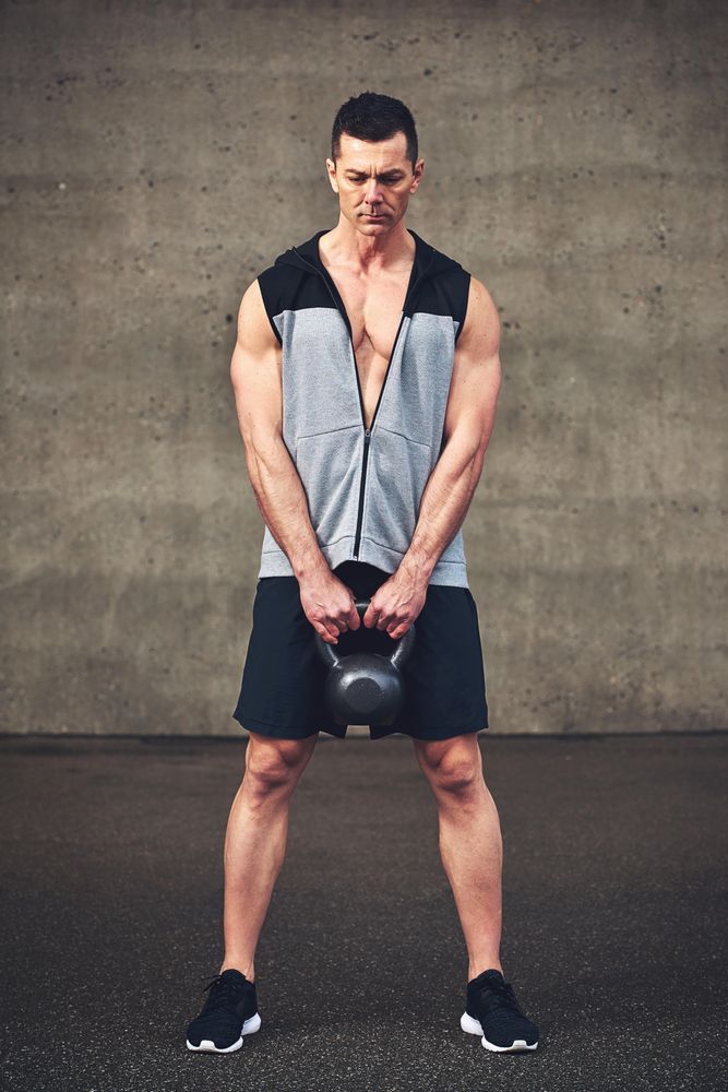 Muscular man with kettlebell in concrete space