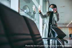 Female traveler having a video call at airport waiting lounge during pandemic 0vYgdb