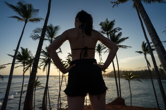 Tranquil female traveler among palms at seashore