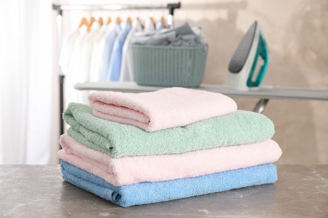 Stack of clean towels on ironing board, space for text