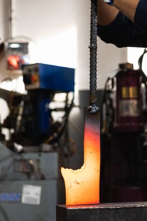 Blacksmiths forging hot metal with hammer in workshop