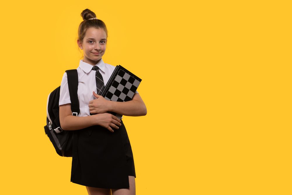 Schoolgirl holds achessboard, ready for game.