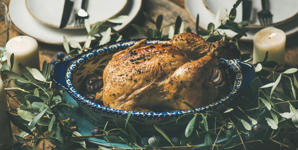 Centerpiece of roast chicken with decorative branches, candles, wide composition