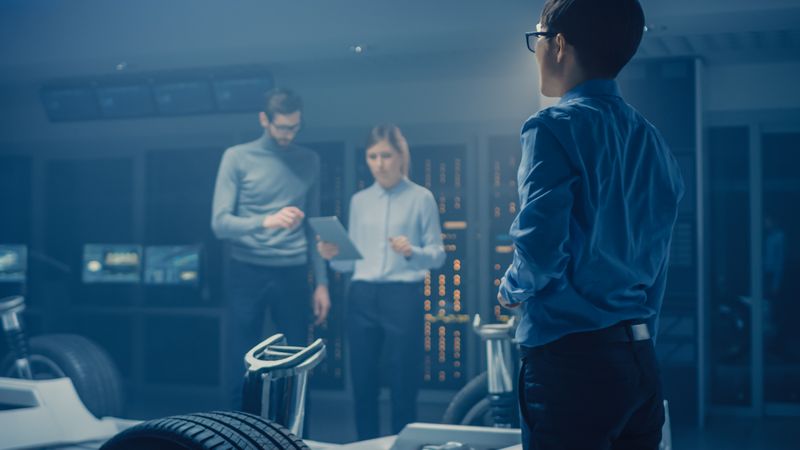 Automobile Engineers Discussing and Designing Electric Car Chassis Platform, Using Tablet Computers with 3D CAD Software.