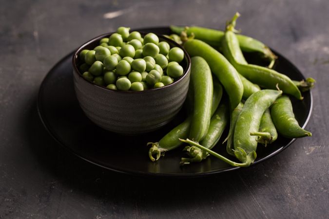 Fresh peas and pea pods on dark background