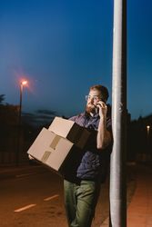 Dedicated courier phoning for delivery completion while waiting client on street in evening