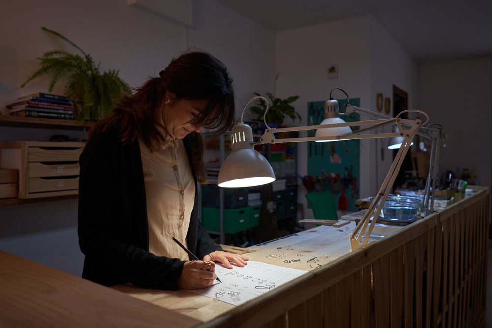Focused female goldsmith creating images of jewelry