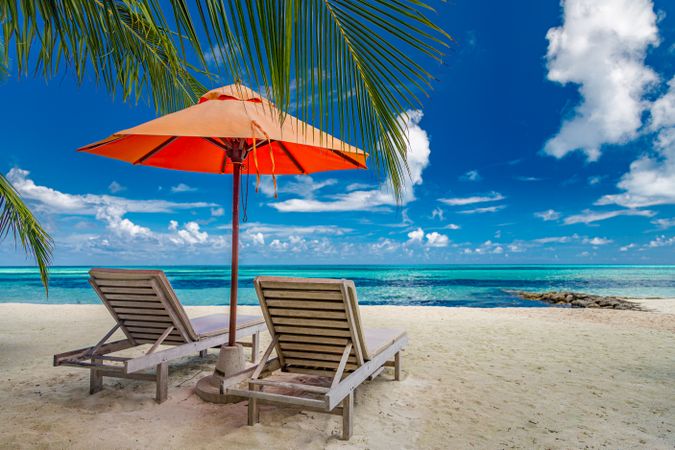 Two lounge chairs overlooking clear water on a beautiful beach
