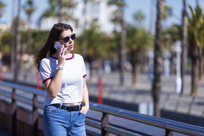 Serious woman in sunglasses using phone on sunny day