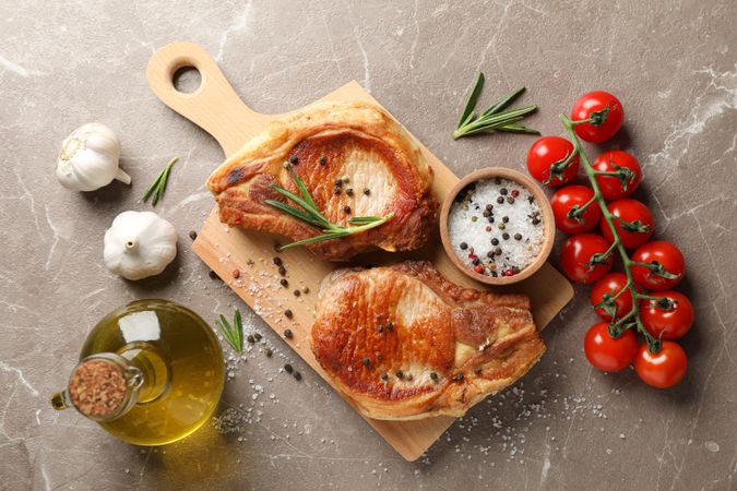Composition with fried steaks and ingredients on gray background. Grilled food