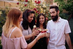Group of cheerful friends clinking glasses at party