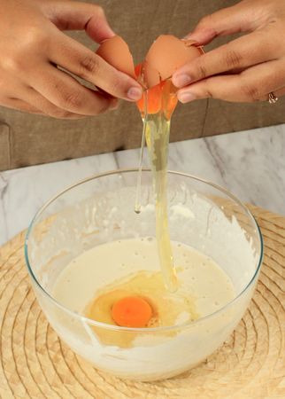 Person cracking egg into bowl of batter