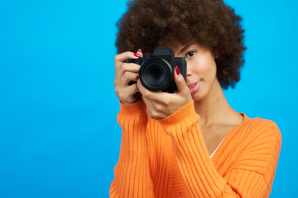 Portrait of a photographer covering her face with her camera while taking a picture