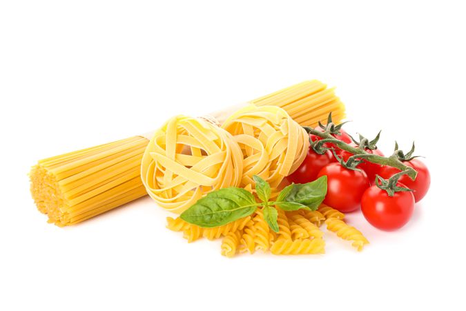 Pasta and vegetables isolated on bright background. Uncooked whole wheat pasta