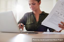 Shot of young woman sitting at table with documents working on laptop computer 4ZKLnb