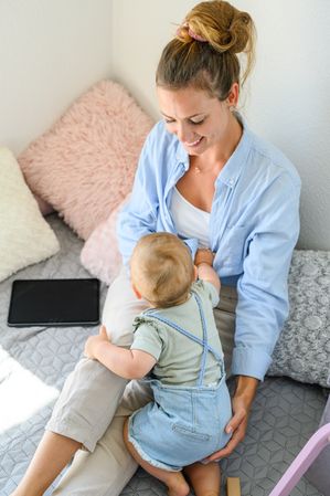 Happy woman with little baby on bed