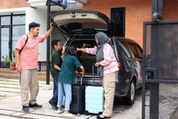 Indonesian Young Family Preparing for Trip in front of Their House, with Suitcases