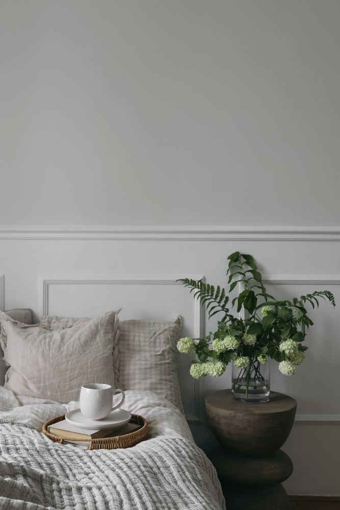 Bed with tray of coffee and glass vase with flowers