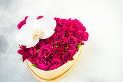St. Valentine Day heart shaped box full of red roses on stone background with copy space