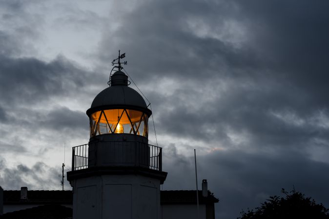 Shining lighthouse against cloudy sky