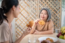 Two Asian women enjoying croissants for breakfast in nook