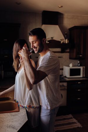 Man embracing girlfriend and drinking water