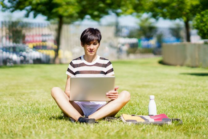 Woman sitting cross legged in park with computer