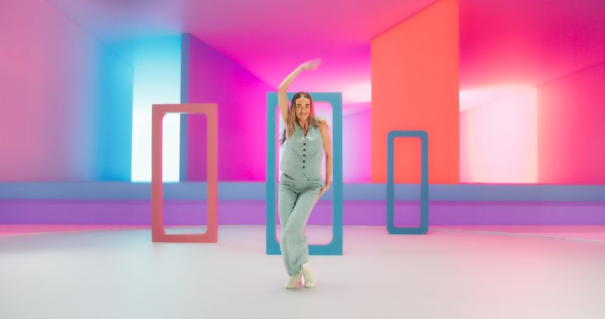 White Woman with Bright Makeup Dancing Energetically and Interacting with Colorful Geometric Abstract Environment. Creative Young Female Happily Performing Modern Dance Choreography in a Studio