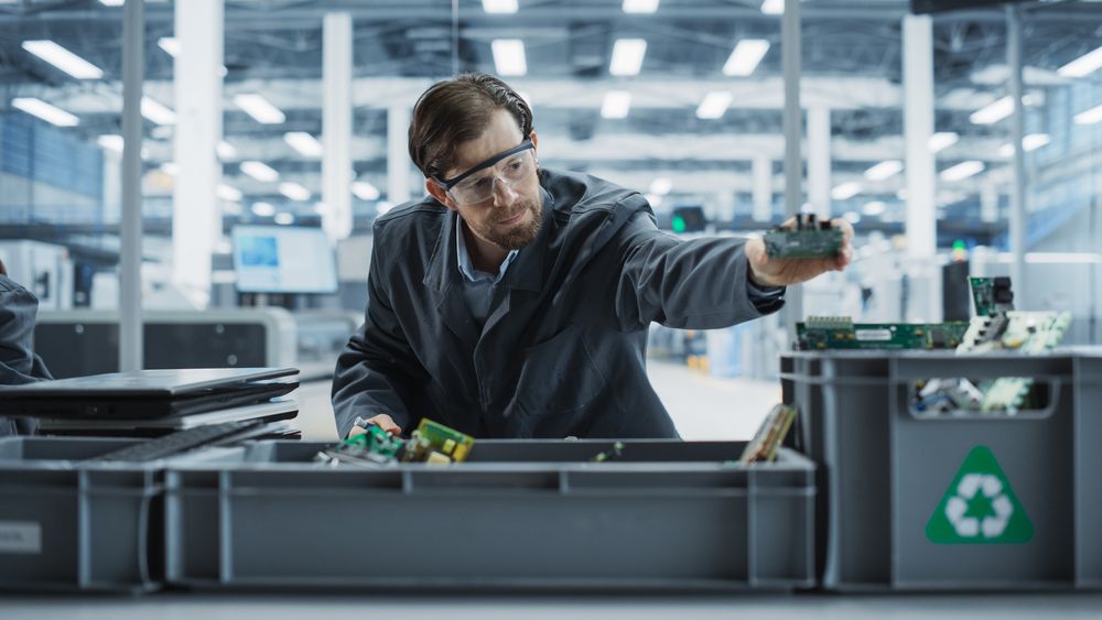 Male Worker Disassembling Old Laptops To Recycle Electronic Components For Sustainable Microchip Production At Electronics Factory.