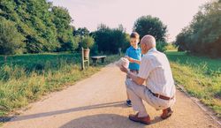 Grandfather showing his hat to grandchild outdoors